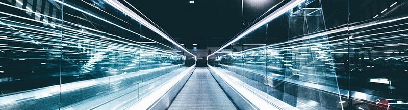 Grey conveyor between glass frames at night